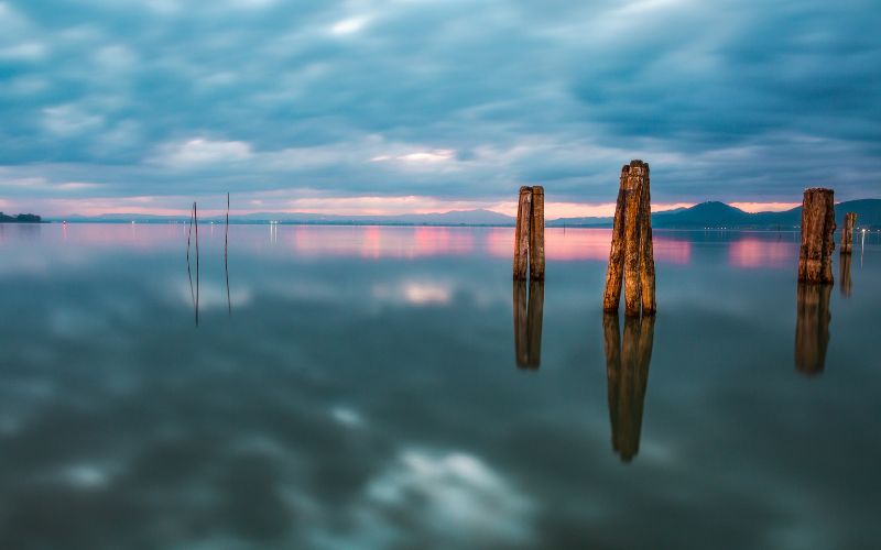 four wood pillars sticking out of a body of water