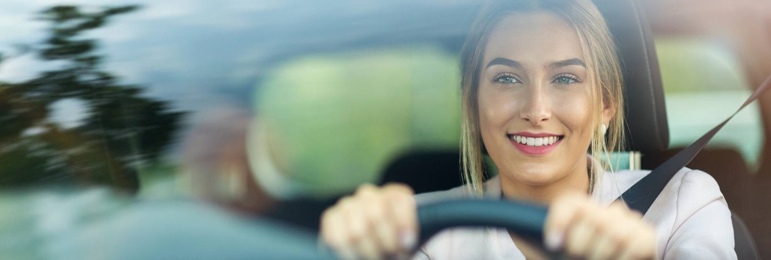 image through windshield showing smiling woman driving